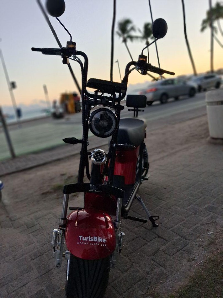 Moto elétrica vermelha TurisBike no calçadão ao pôr do sol